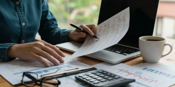 Detailed spreadsheet on laptop screen with hands analyzing data, symbolizing personal budgeting for inflation.