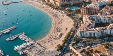 Paisaje costero español con turistas y hoteles, simbolizando el crecimiento turístico.