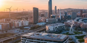 Sunrise over a Spanish city with integrated wind turbines and solar panels, symbolizing green tech investment and sustainable urban development.